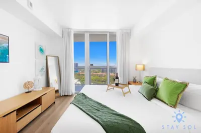 a white bedroom with a large bed with green pillows at Stylish 1BR High Rise Retreat w Ocean View in Hallandale Beach