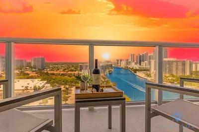 a view of a city skyline from a balcony with a bottle of wine at Stylish 1BR High Rise Retreat w Ocean View in Hallandale Beach