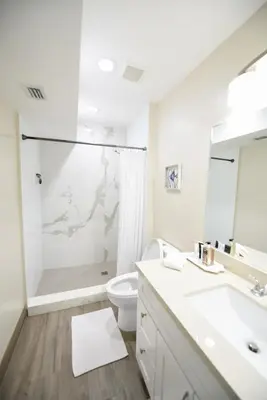 a white bathroom with a shower and a toilet at The Hamptons Hideaway in Hollywood