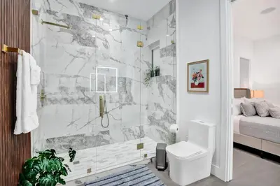 a white bathroom with a shower and a toilet at New Luxe Contemporary Home 4BR-4BA with Heated Pool, Mini Golf, Pool table in Fort Lauderdale