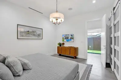 a bedroom with a bed and a table in a room at New Luxe Contemporary Home 4BR-4BA with Heated Pool, Mini Golf, Pool table in Fort Lauderdale