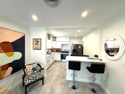 a kitchen with a counter and two bar stools at The Pines Hideaway-Your Home Away from Home in Fort Lauderdale