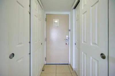 a hallway with white doors and a tile floor at Oceanfront Resort Condo with Gym and Waterfront Pool! in Sunny Isles Beach