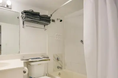 a white bathroom with a toilet and a sink at Oceanfront Resort Condo with Gym and Waterfront Pool! in Sunny Isles Beach