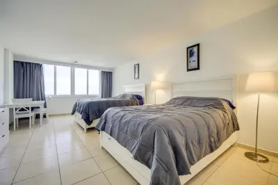 a hotel room with two beds and a desk at Oceanfront Resort Condo with Gym and Waterfront Pool! in Sunny Isles Beach