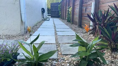 a garden with a stone walkway next to a fence at The Garden House in Miami Lakes in Miami Lakes