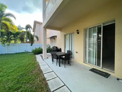 a patio with a table and chairs next to a house at The Garden House in Miami Lakes in Miami Lakes