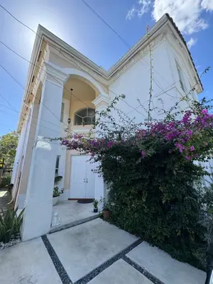 a white house with a bush with purple flowers at The Garden House in Miami Lakes in Miami Lakes