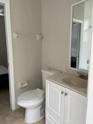 a white bathroom with a toilet and a sink at The Garden House in Miami Lakes in Miami Lakes
