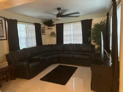 a black leather couch in a living room with a ceiling fan at Miramar near Hard Rock stadium in Miramar