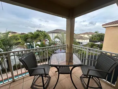 a balcony with a glass table and two chairs at The Miami Lakes Pool House in Miami Lakes