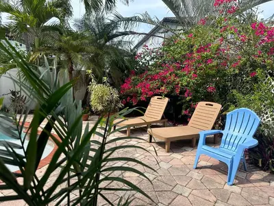 a group of chairs sitting on a patio with flowers at The Miami Lakes Pool House in Miami Lakes