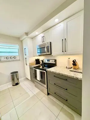 a kitchen with white cabinets and a stove top oven at Modern 2 bedroom condo with heated pool, free parking spot at a 5 minute walk to the beach! in Sunny Isles Beach