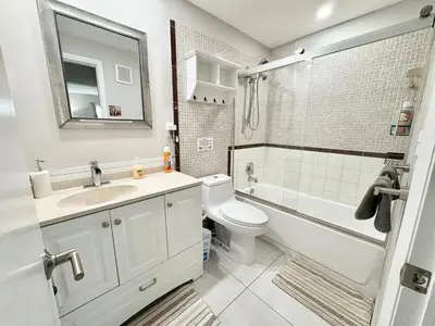 a bathroom with a sink and a toilet and a bath tub at Modern 2 bedroom condo with heated pool, free parking spot at a 5 minute walk to the beach! in Sunny Isles Beach