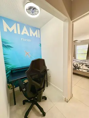 a room with a desk and a chair next to a bed at Modern 2 bedroom condo with heated pool, free parking spot at a 5 minute walk to the beach! in Sunny Isles Beach