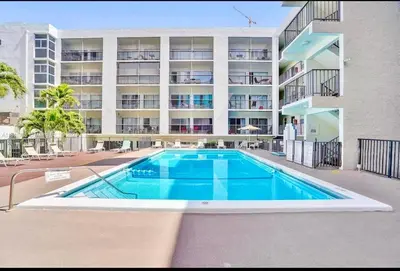 a swimming pool in front of a building at Modern 2 bedroom condo with heated pool, free parking spot at a 5 minute walk to the beach! in Sunny Isles Beach