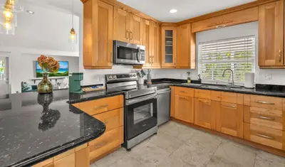 a kitchen with wooden cabinets and black counter tops at Casa Verde - Wilton Manors - Pool in Fort Lauderdale