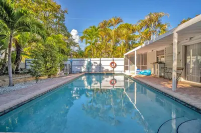 a swimming pool in front of a house with trees at Casa Verde - Wilton Manors - Pool in Fort Lauderdale