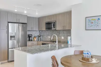 a kitchen with a stainless steel refrigerator and a table at Doral 2BD Condo with Skyline Views and Fitness Center in Miami