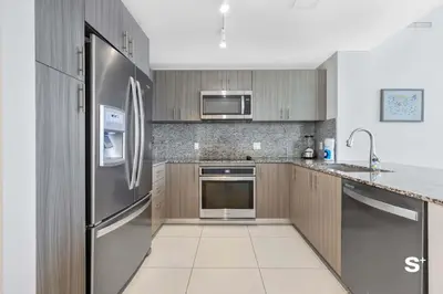 a kitchen with stainless steel appliances and wooden cabinets at Doral 2BD Condo with Skyline Views and Fitness Center in Miami