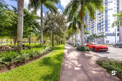 a red car parked on a street with palm trees at Modern 1BR in Downtown Doral - Free Parking and Wellness Amenities in Miami
