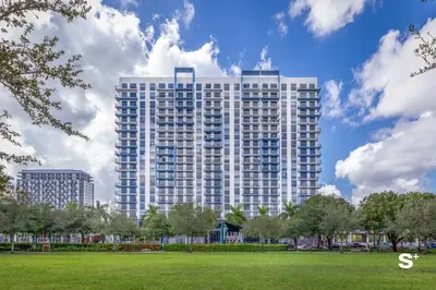 a tall building with a park in front of it at Modern 1BR in Downtown Doral - Free Parking and Wellness Amenities in Miami