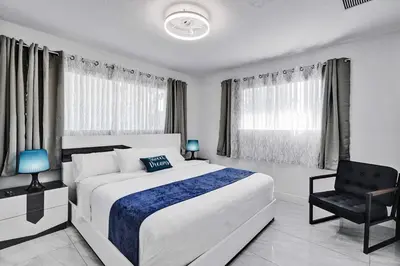 a bedroom with a large white bed and a chair at WALK to Hollywood Beach Stylish 5BR and 4BA Villa in Hollywood