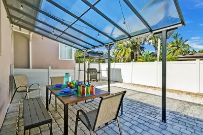 a patio with a table and chairs under a pergola at WALK to Hollywood Beach Stylish 5BR and 4BA Villa in Hollywood