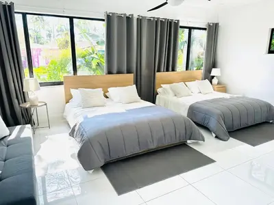 two beds in a white room with windows at Palm Breeze Getaway in Hollywood