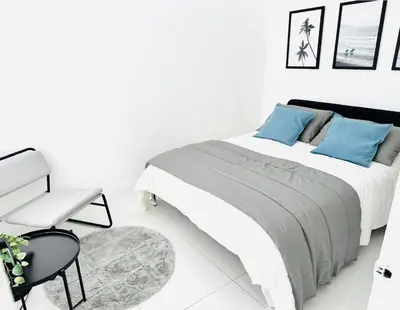 a white bedroom with a bed and a chair at Palm Breeze Getaway in Hollywood
