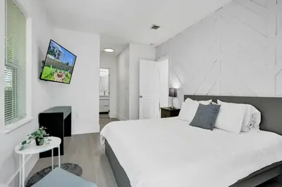a white bedroom with a large bed and a table at Palm Breeze Retreat in Hollywood