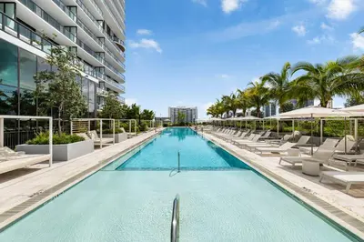 a swimming pool with lounge chairs and a building at Newest & Elegant Condo - 72 Park in Miami Beach
