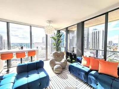 a living room with a blue couch and large windows at 3BR Skyline Luxury with a 100 inch TV, Balcony & Prime Miami Location in Miami