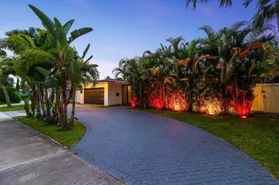 a driveway leading to a house with palm trees and lights at Lakefront Villa Tropical Backy in North Miami Beach