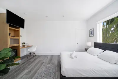 a white bedroom with a bed and a tv at St Augustine Hotel By At Mine Hospitality in Miami Beach