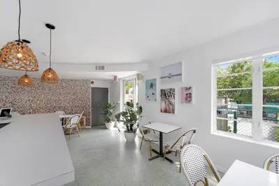 a dining room with white walls and tables and chairs at St Augustine Hotel By At Mine Hospitality in Miami Beach