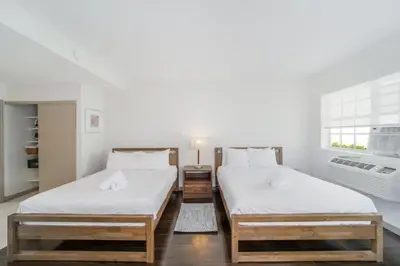 two twin beds in a room with a window at Casa Colaretta By At Mine Hospitality in Miami Beach