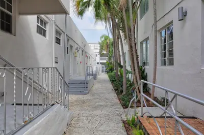a walkway between two buildings with palm trees at Casa Colaretta By At Mine Hospitality in Miami Beach