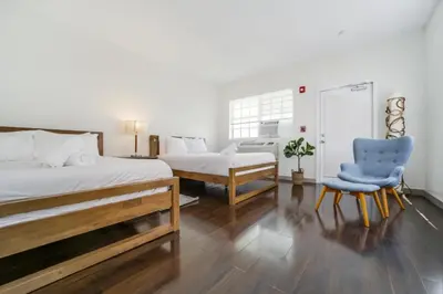 a bedroom with a bed and a blue chair at Casa Colaretta By At Mine Hospitality in Miami Beach