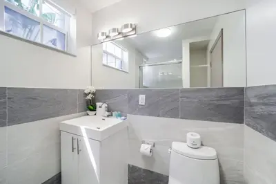 a bathroom with a toilet and a sink and a mirror at Casa Colaretta By At Mine Hospitality in Miami Beach