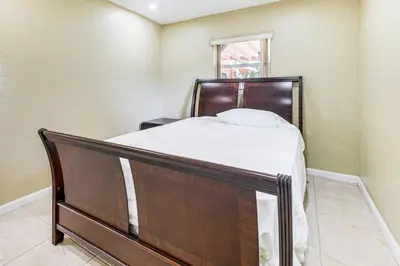a bedroom with a bed with a wooden headboard and a window at 3 Mi to Dania Beach Pier Convenient Apartment! in Dania Beach