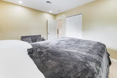 a bedroom with a large bed and a chair at 3 Mi to Dania Beach Pier Convenient Apartment! in Dania Beach