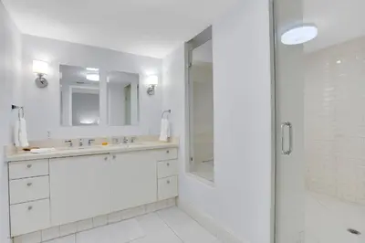 a white bathroom with a shower and a sink at 2BR Art Deco Retreat Steps Away from the Beach in Miami Beach