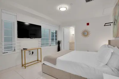a white bedroom with a bed and a flat screen tv at 2BR Art Deco Retreat Steps Away from the Beach in Miami Beach