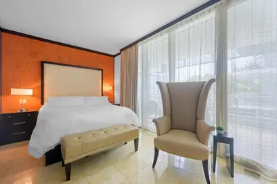 a bedroom with a large bed and a chair at Luxury Suite - 3 Min Walk to Miami Beach in Miami Beach