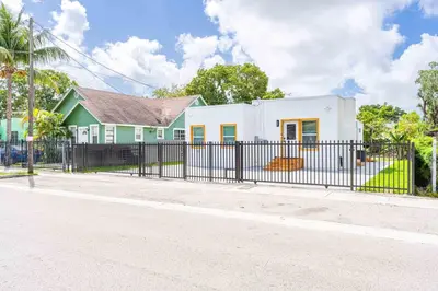 a white house with a fence in front of a street at Modern Miami Home minutes to Wynwood & Downtown in Miami