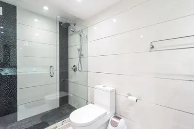 a white bathroom with a toilet and a shower at Large 2 Bedroom Oceanfront at Roney Palace in South Beach in Miami Beach