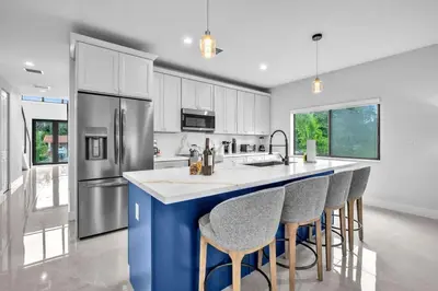 a kitchen with a blue island with bar stools at Casa Amoret - Brand New Family-Friendly Retreat in Miami