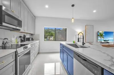a white kitchen with blue cabinets and a sink at Casa Amoret - Brand New Family-Friendly Retreat in Miami