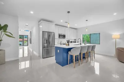a kitchen with a blue island with bar stools at Casa Amoret - Brand New Family-Friendly Retreat in Miami